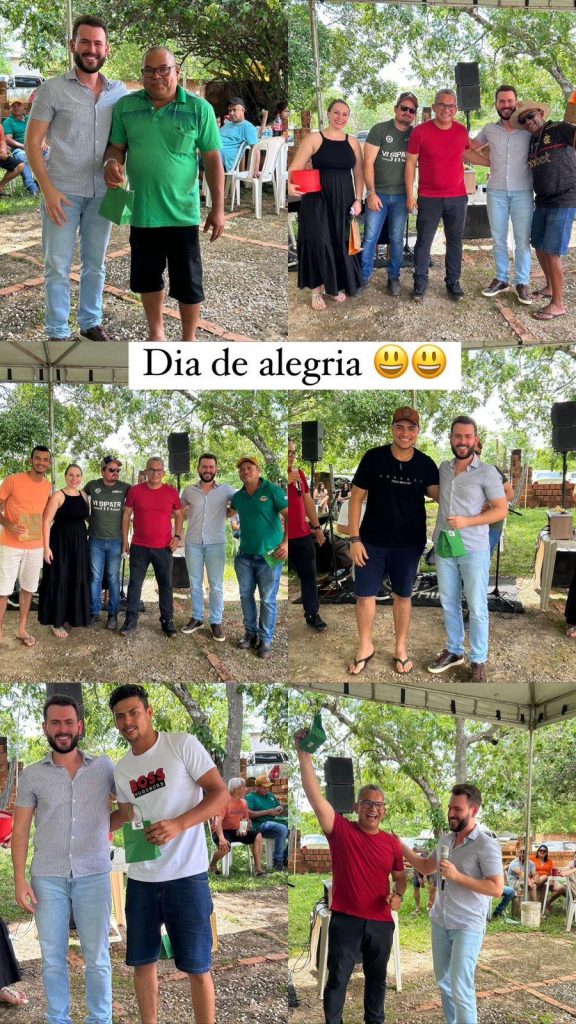 Vários participantes do evento posando para fotos em grupo, alguns segurando prêmios e pacotes. Um banner central da imagem diz "Dia de alegria 😀😀", reforçando o tom festivo do dia. O ambiente conta com uma estrutura coberta e mesas ao fundo.